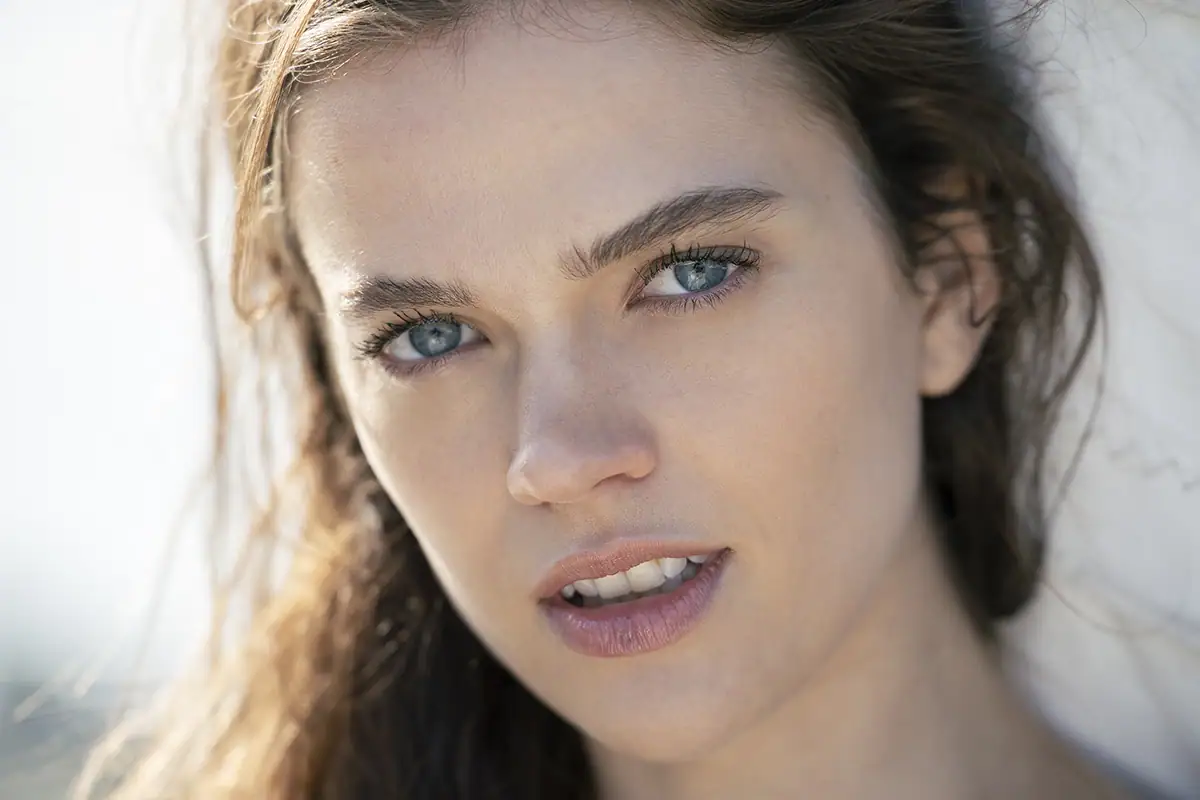 Portrait d'été en gros plan d'une femme à la lumière naturelle, démontrant un flou d'arrière-plan doux et des techniques d'éclairage pour la photographie d'été.