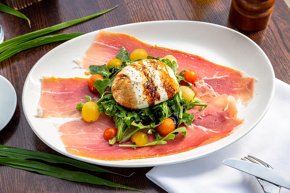 Burrata and prosciutto salad photographed in a restaurant setting, demonstrating food styling in restaurants and fast-paced food photography techniques.