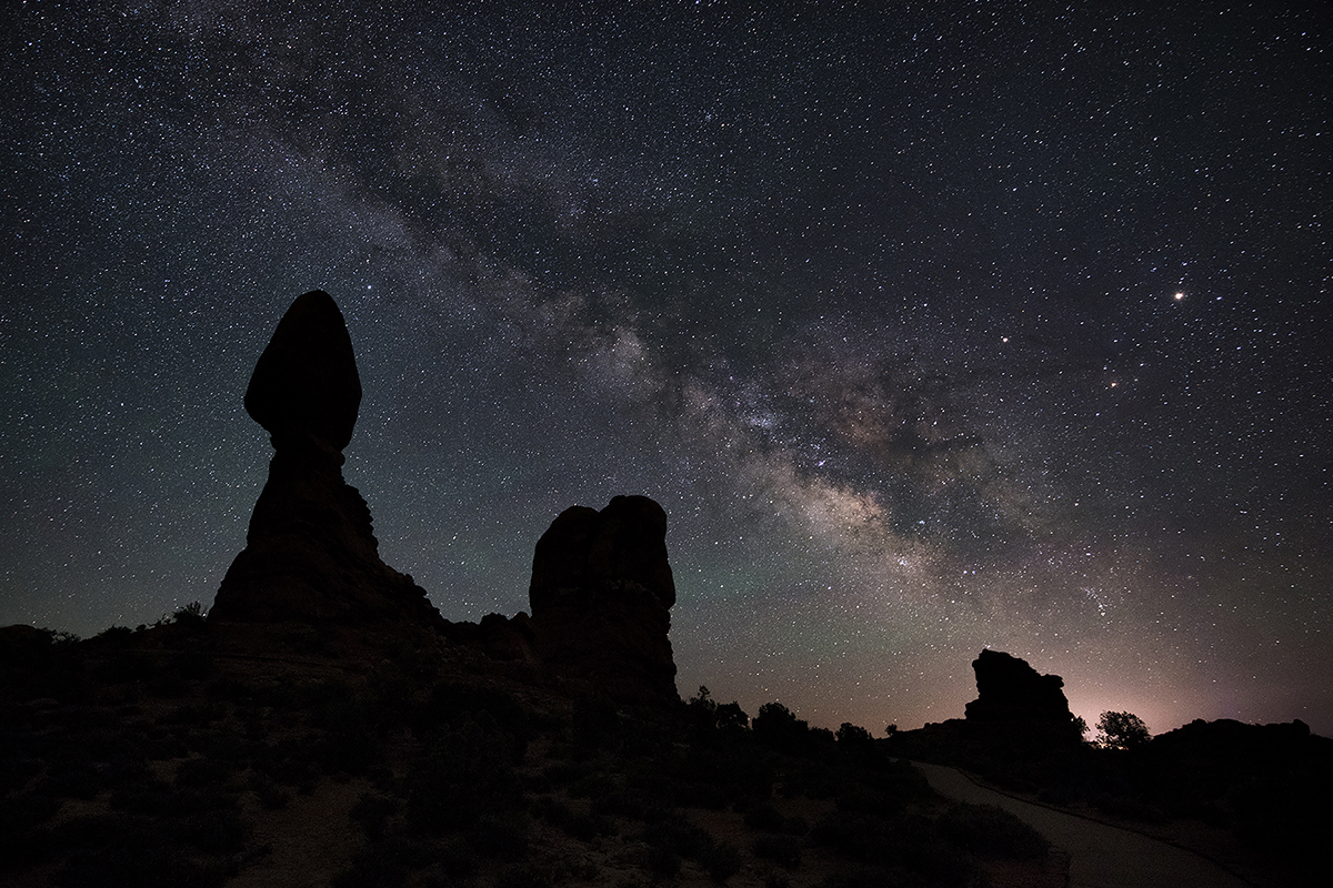 Silhouette of desert rock formations under a star-filled sky and the Milky Way, demonstrating night sky photography tips like foreground composition and long exposure.