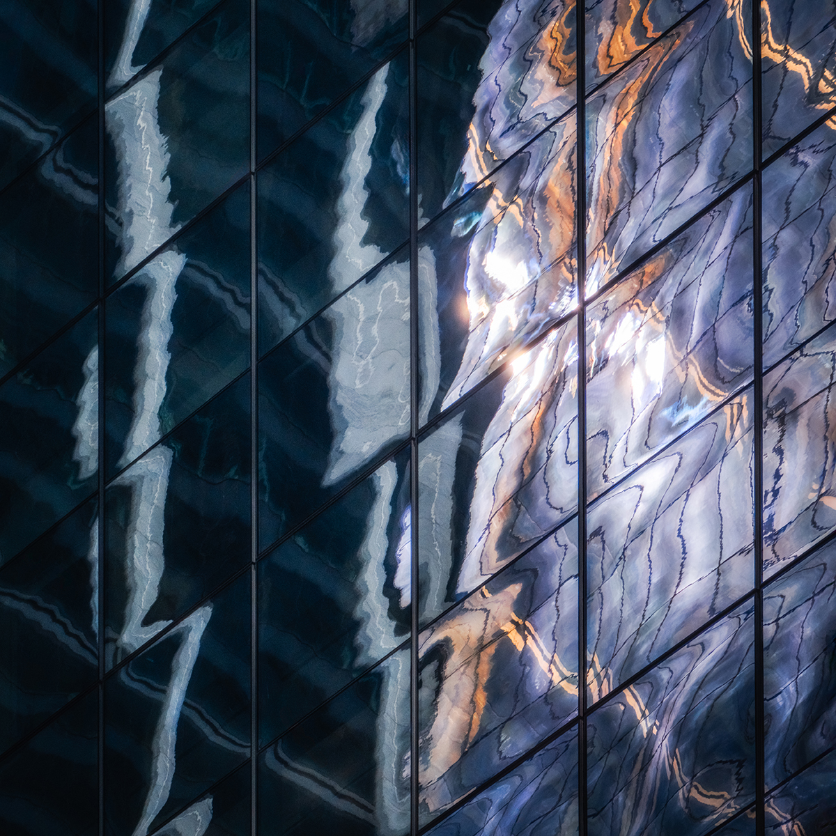 Reflexo abstrato da luz e da arquitetura em janelas de vidro, mostrando técnicas de fotografia abstrata por meio de distorção, cor e enquadramento geométrico.