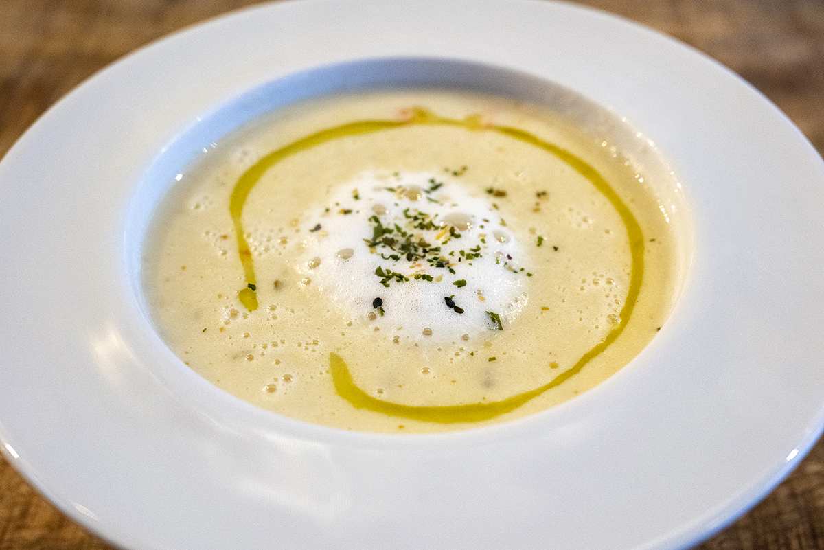 Creamy soup artfully plated with herb garnish and olive oil swirl, captured using natural lighting&mdash;an example of Insta-worthy food photography tips in action.