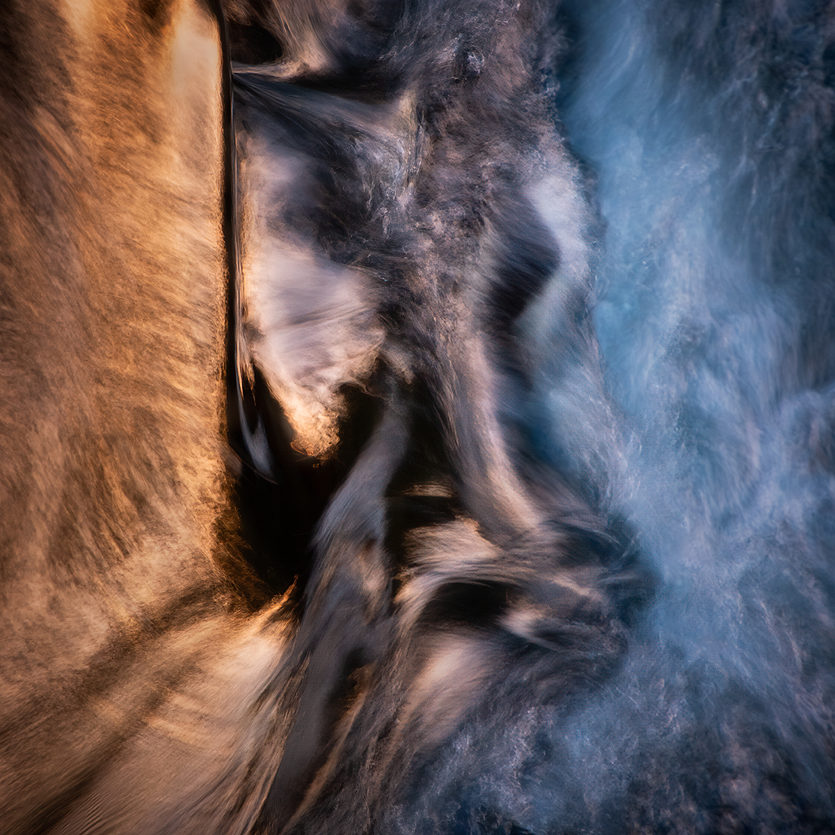 Imagem de longa exposição mostrando água corrente em tons quentes e frios, demonstrando técnicas de fotografia abstrata com desfoque de movimento e contraste de cores.