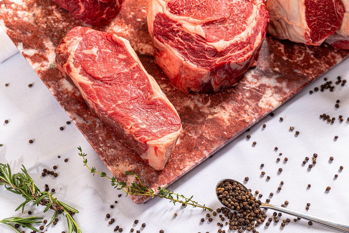 Raw steaks styled for restaurant food photography using depth of field in food photography and food photography lighting techniques.