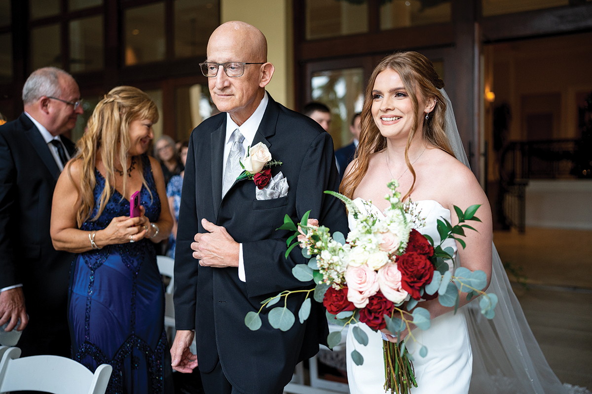 Une mariée sourit alors qu'elle descend l'allée avec son père, magnifiquement capturée lors d'une cérémonie de mariage - un exemple de composition experte et de narration émotionnelle présenté dans ces conseils de photographie de mariage par Scott Stockton.
