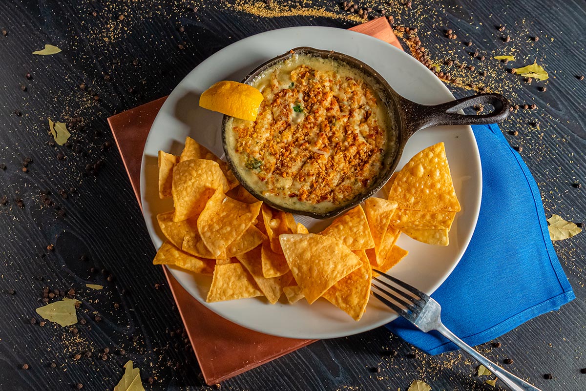 Artichoke dip with tortilla chips styled for on-location food photography in a restaurant setting using fast-paced food photography techniques.