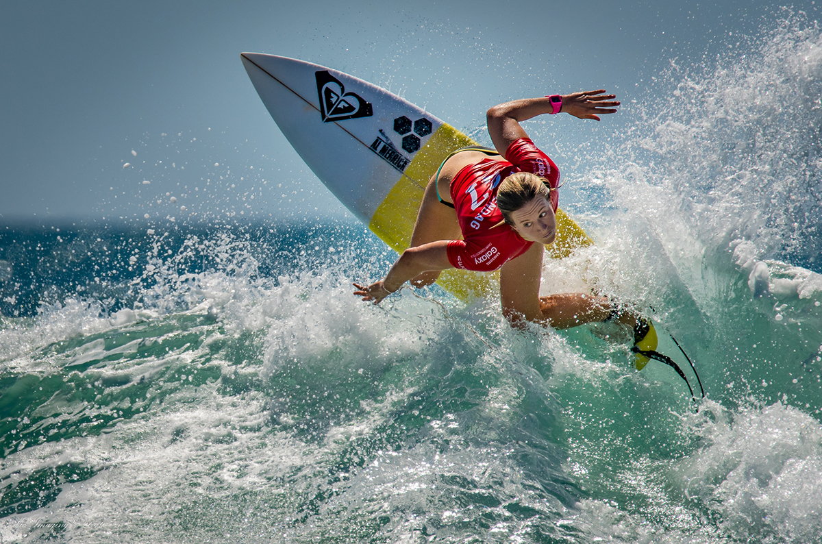 Un surfista atraviesa una ola rompiendo con intensidad y control: un ejemplo perfecto de cómo aplicar los consejos de la fotografía deportiva para captar el movimiento y la emoción.