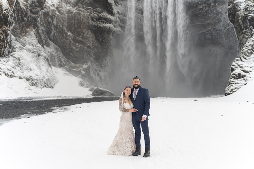 A bride and groom pose in front of a frozen waterfall in Iceland, captured with exceptional clarity and depth by the Tamron 35-150mm F2-2.8&mdash;showcasing the lens's versatility for impromptu portraits in extreme conditions during this hands-on review.