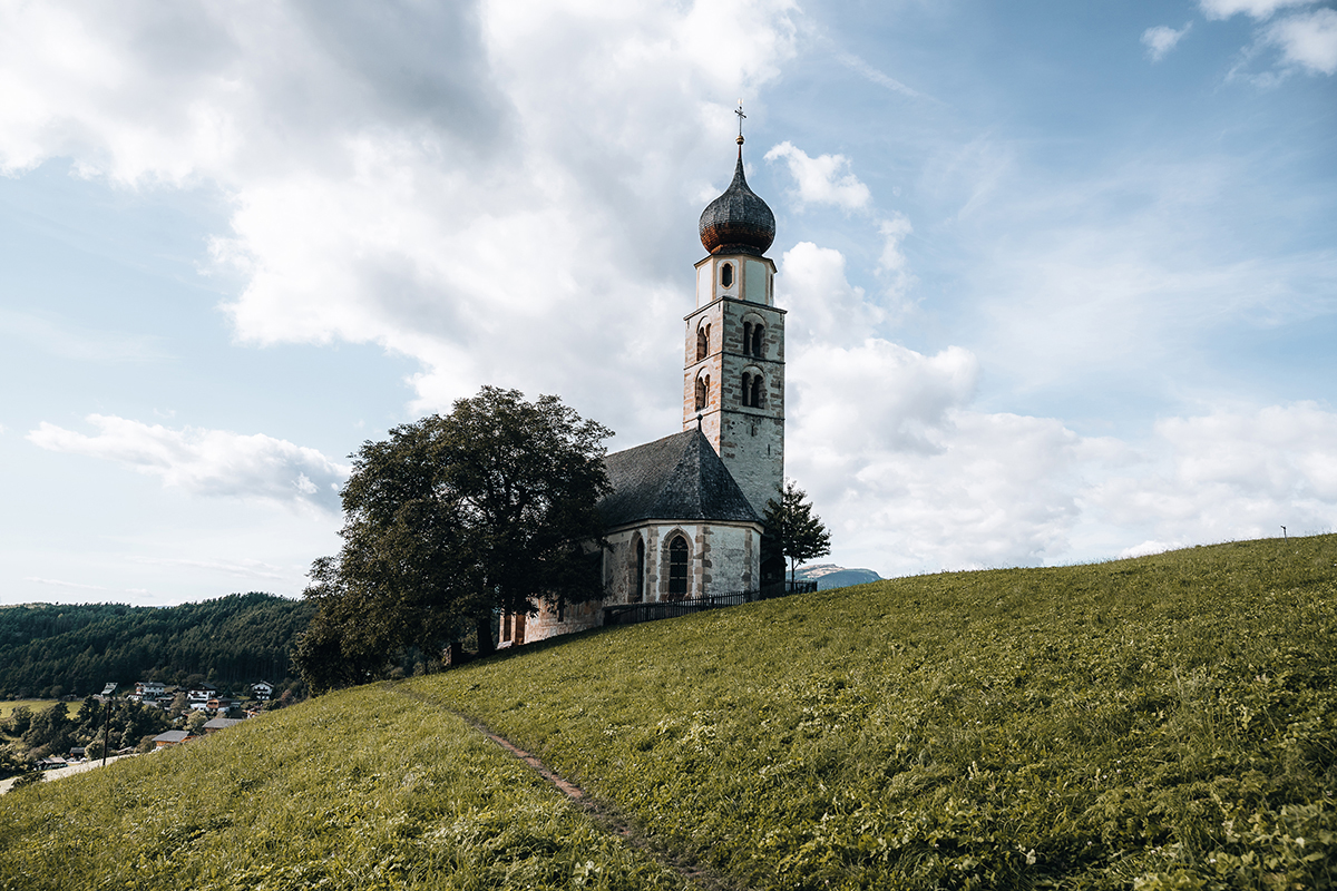 Igreja histórica no topo de uma colina sob um céu dramático, capturada com a lente Tamron 17-70 mm para paisagens usando uma câmera sem espelho da Sony.