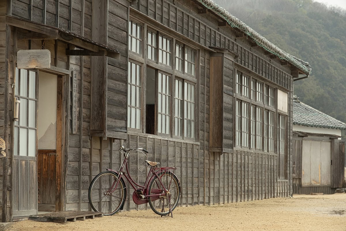 Una bicicleta antigua descansa frente a un edificio de madera desgastada: un ejemplo de los consejos de la fotografía local para captar la textura y el encanto nostálgico.