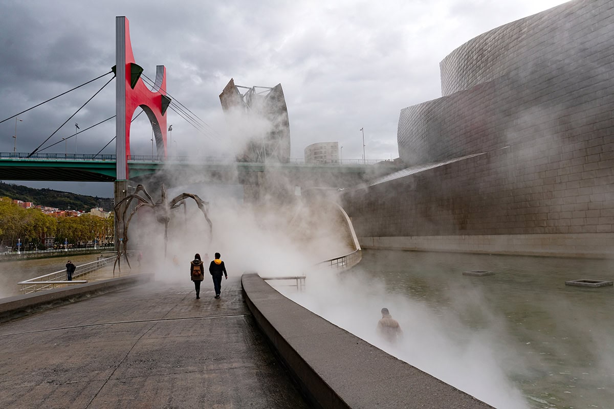 Foggy urban walkway near Guggenheim Bilbao captured with atmospheric lenses for street photography.