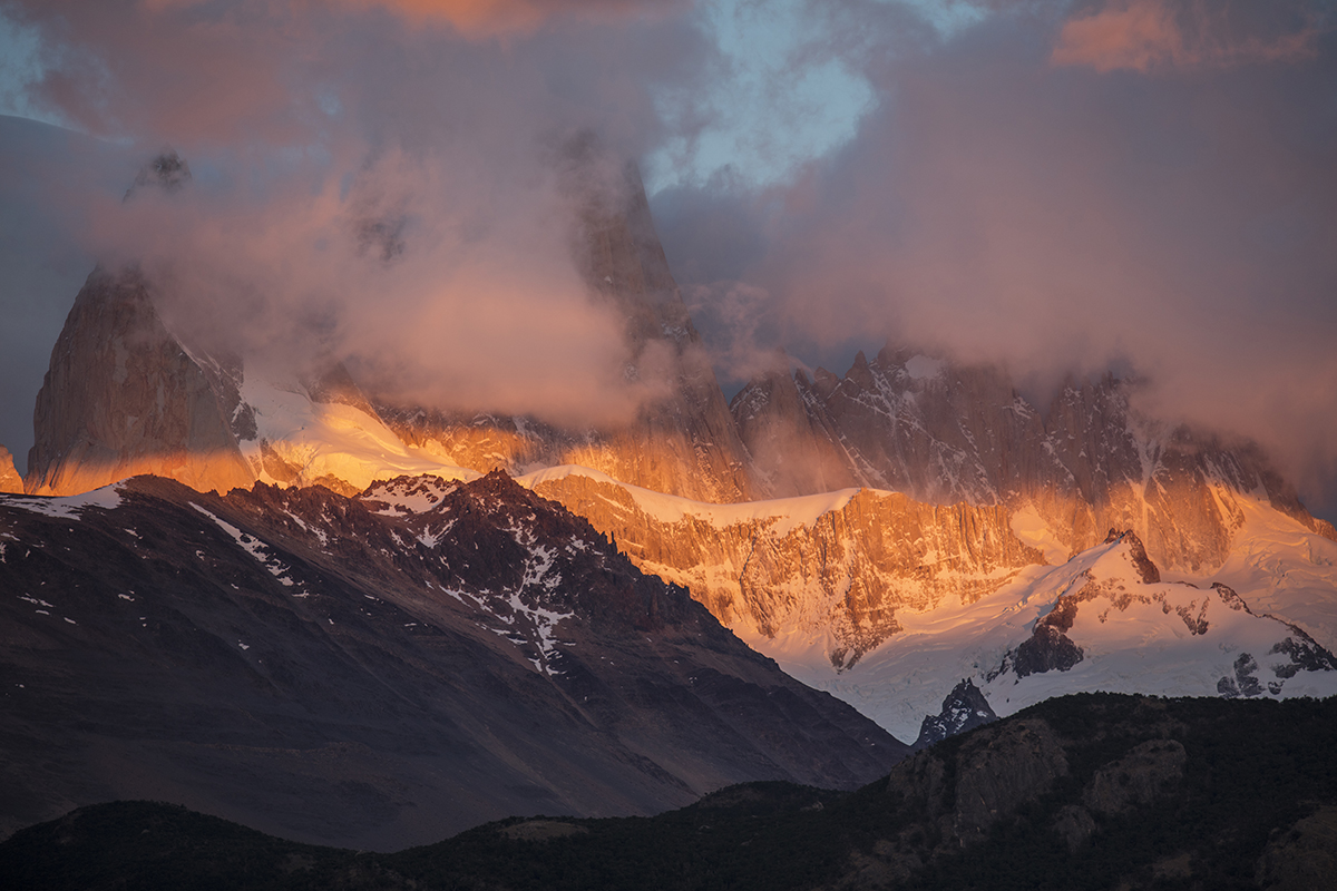 Un coucher de soleil spectaculaire illumine les sommets enneigés des montagnes à travers les nuages d'orage. La photo a été prise avec un matériel de photographie d'hiver soigneusement entretenu pour assurer la clarté et le contraste.