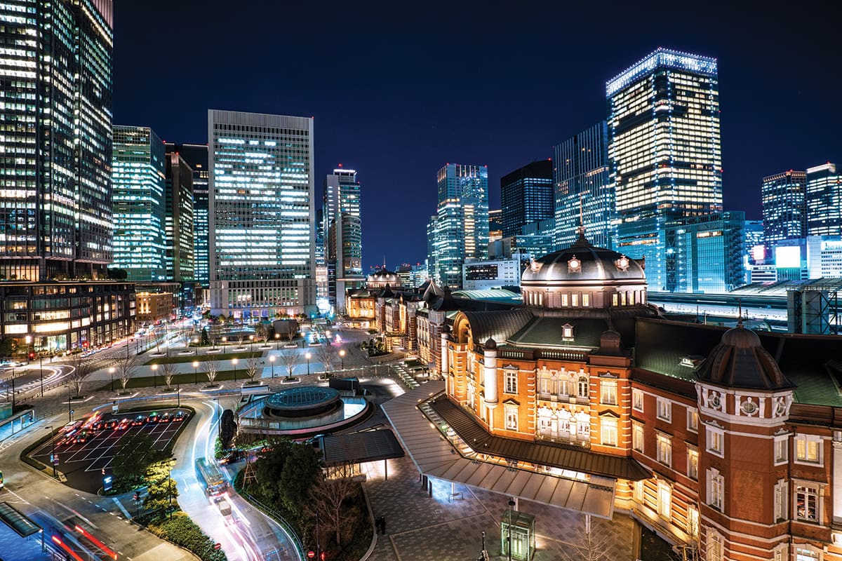 Tokyo Station illuminated at night, surrounded by modern skyscrapers&mdash;highlighting contrast and lighting in urban architecture photography.