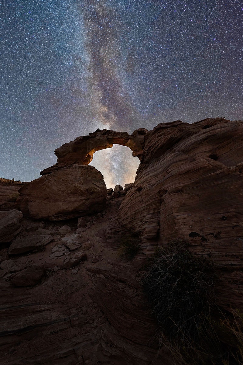 Imagen astrofotográfica de la Vía Láctea enmarcada por un arco de roca natural en el desierto, mostrando consejos de expertos para la composición astrofotográfica. @Jonny Hill
