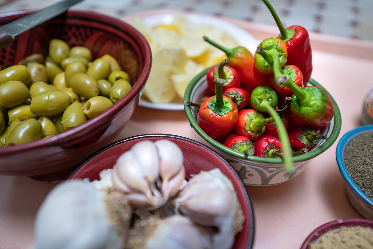 Rustic tabletop display of fresh olives, garlic, peppers, and spices in colorful bowls&mdash;captured using natural light and shallow depth of field, following Insta-worthy food photography tips.