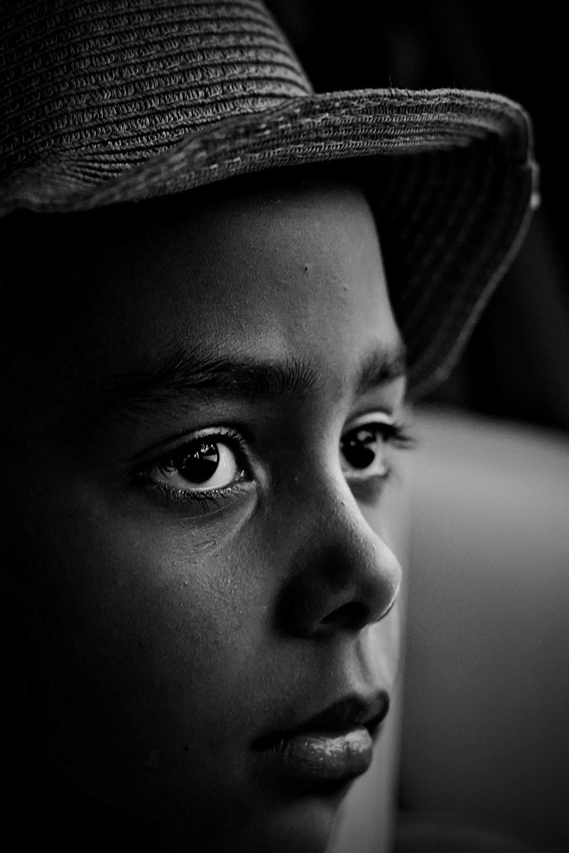 Fotografía creativa en primer plano de un niño con un sombrero texturizado, destacando la rica textura facial y el contraste en una dramática iluminación en blanco y negro.