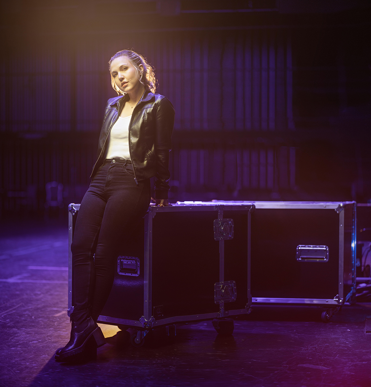 Joven entre bastidores iluminada por geles de colores vibrantes que muestran una iluminación espectacular en la fotografía de retrato.