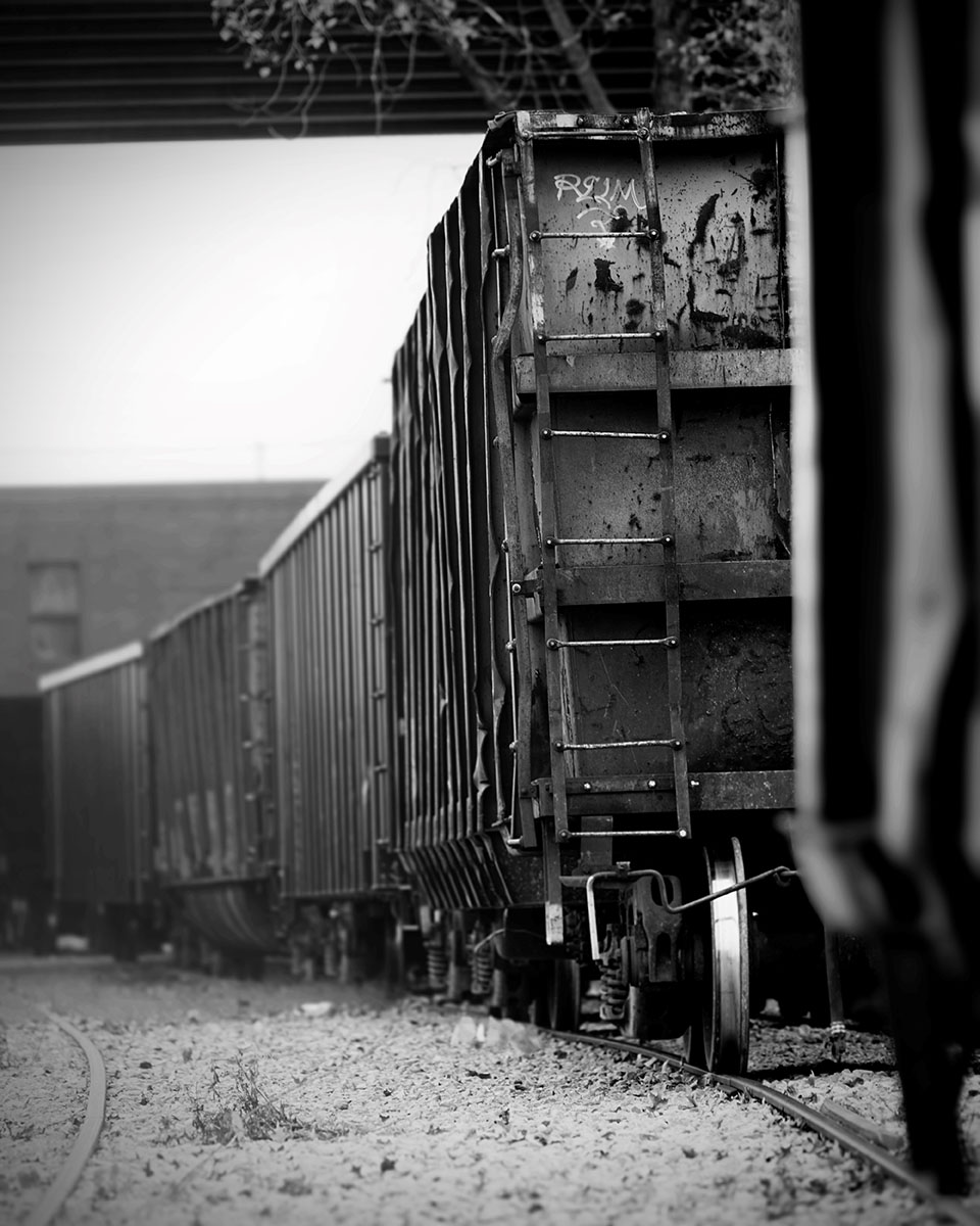 Fotografía creativa en primer plano de un tren desde un ángulo bajo, destacando la profundidad, la textura y la perspectiva con fuertes líneas de dirección en las vías.