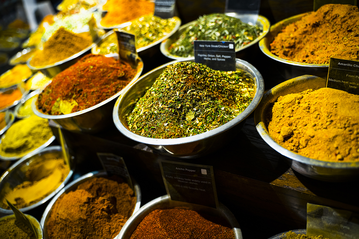 Vibrant display of colorful spices in metal bowls at a market, captured with shallow depth of field to emphasize texture and color&mdash;perfect execution of Insta-worthy food photography tips.