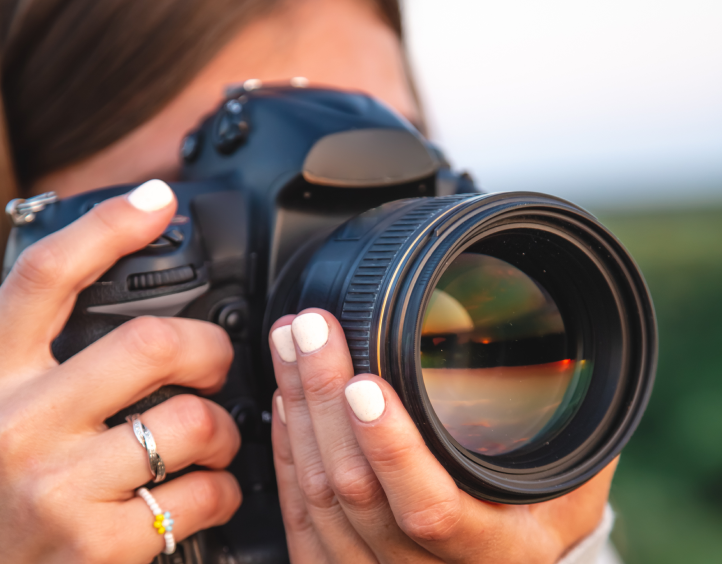 Uma mulher segurando uma câmera com uma lente na altura dos olhos para tirar uma foto