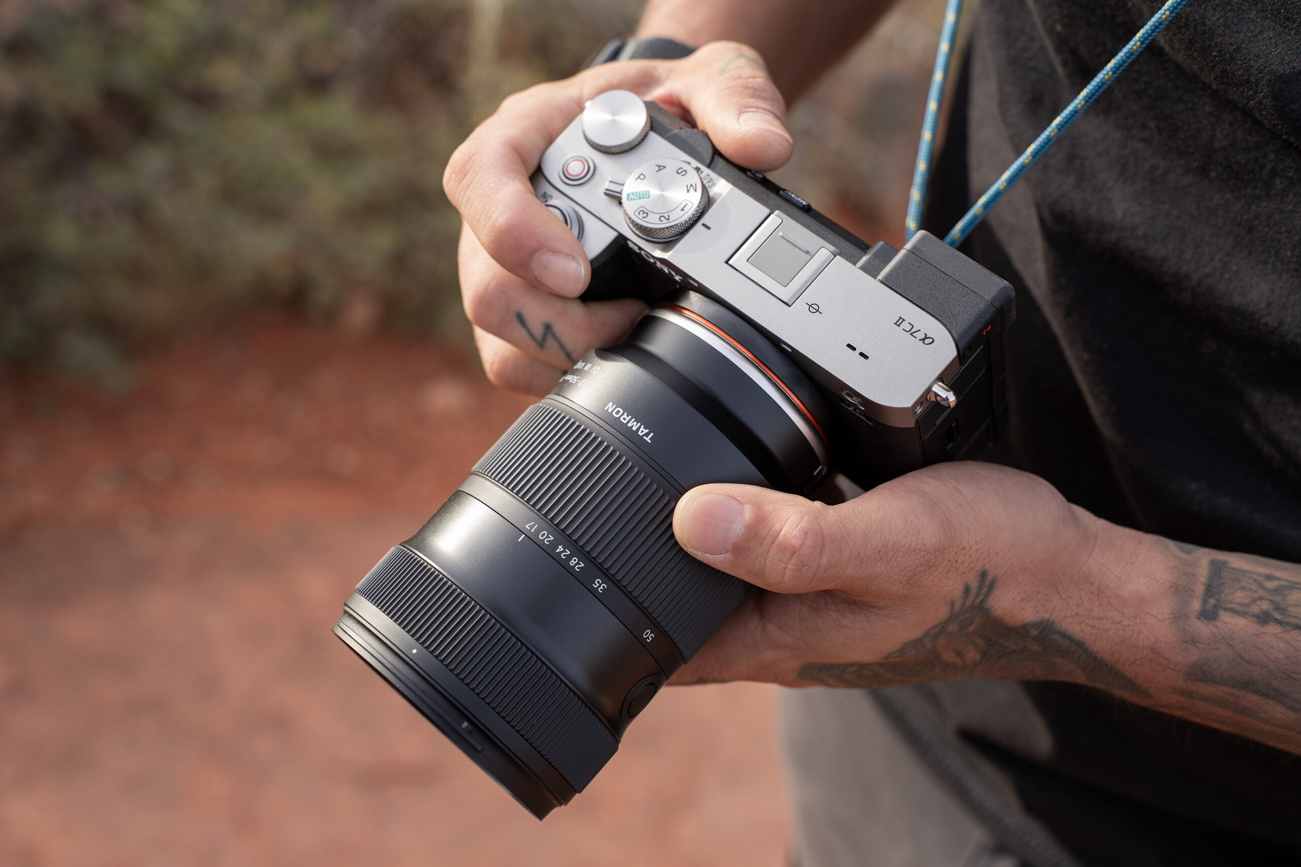 A person holding a camera with the Tamron 17-50mm lens attached.