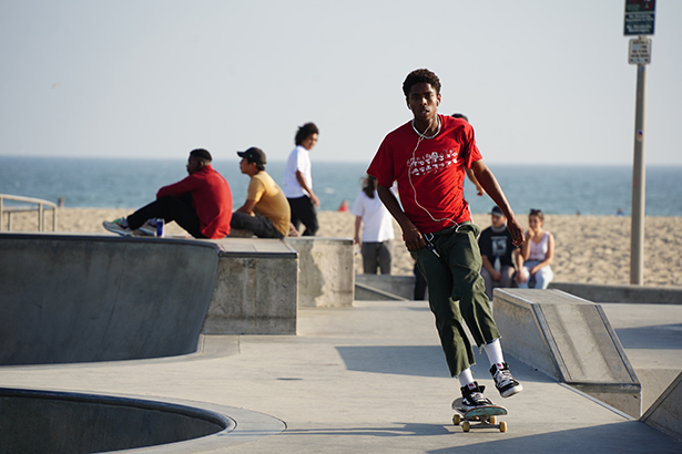 Um skatista desliza em um skatepark iluminado pelo sol perto da praia, demonstrando como tirar fotos de rua capturando o movimento e a energia em espaços públicos. ©Janet Vuong