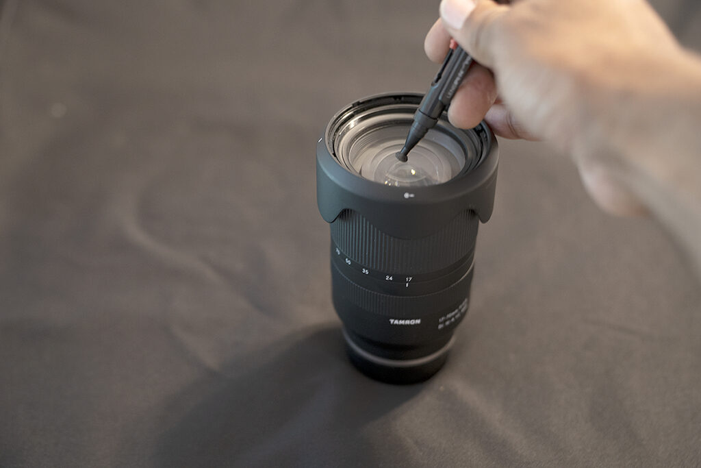 A Tamron lens being cleaned with a fine bristle brush.