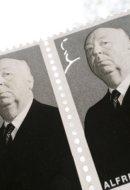 A detailed close-up of two Alfred Hitchcock postage stamps showing ink texture and perforations. &copy;Jillian Bell