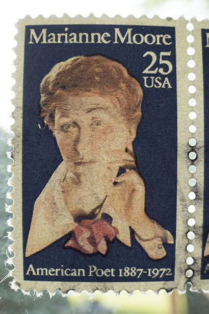 A close-up of a 25-cent USA postage stamp featuring Marianne Moore, labeled &ldquo;American Poet 1887&ndash;1972,&rdquo; with visible perforations and subtle paper texture. &copy;Jillian Bell