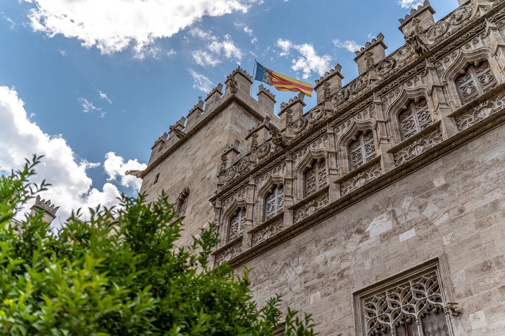 Bâtiment de style gothique orné de sculptures en pierre détaillées et d'un drapeau, vu de dessous - idéal pour mettre en valeur les conseils en matière de photographie d'architecture.