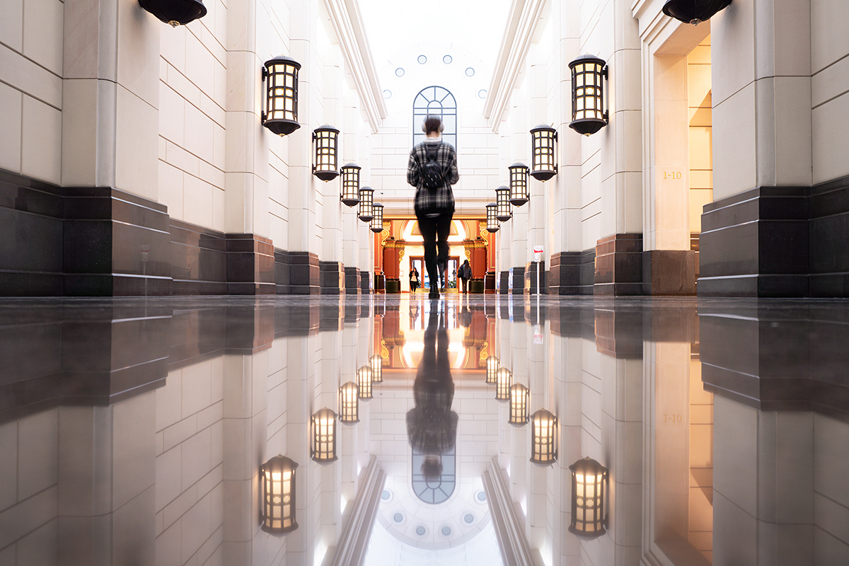 A person walking in a building lit on both sides.