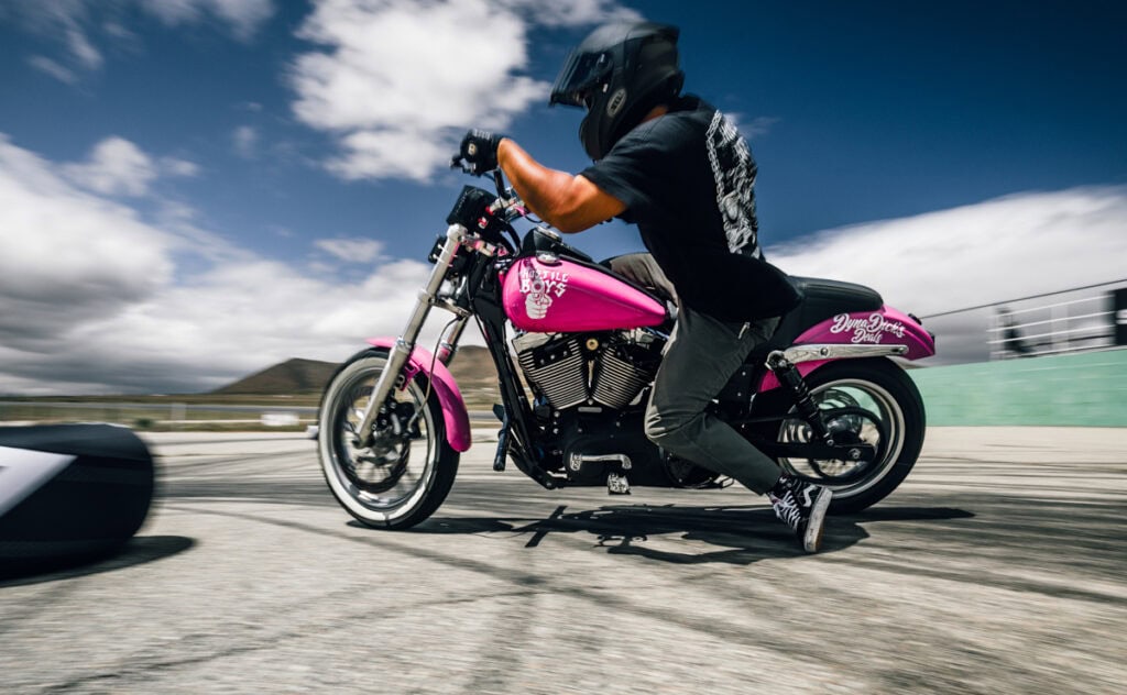 Un homme sur une moto rose vif, lors d'une course de moto drift.