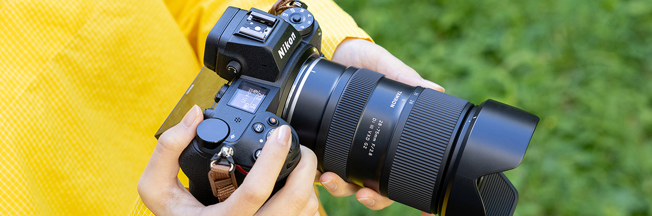A person wearing a yellow jacket holds one of Tamron’s best Nikon Z lenses for wildlife while outdoors.