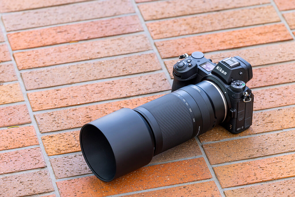 A Nikon camera equipped with a Tamron lens placed on a textured brick service. 
