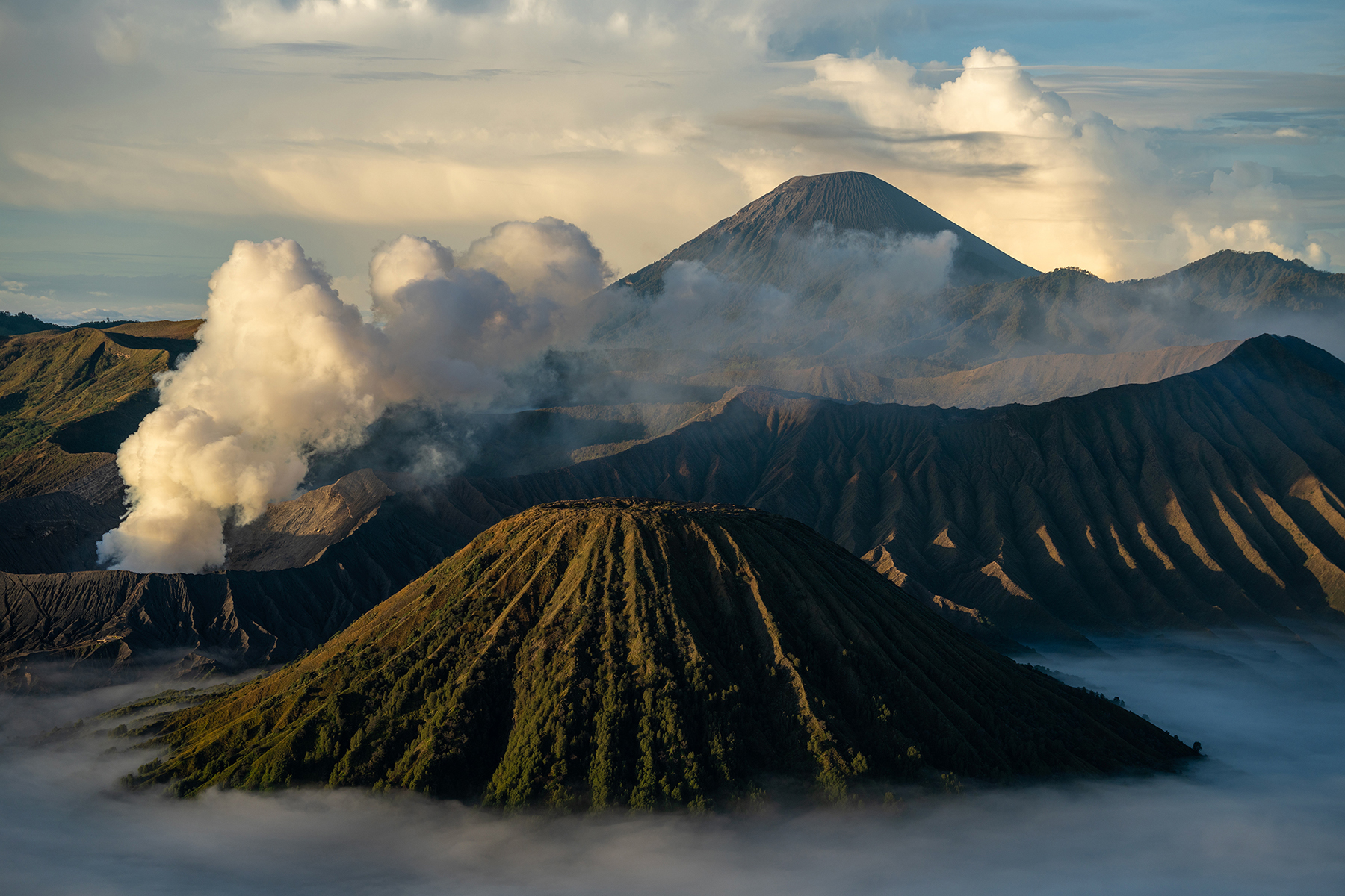 Uma vista inspiradora de uma paisagem vulcânica com crateras fumegantes e vales cobertos de névoa ao nascer do sol.
