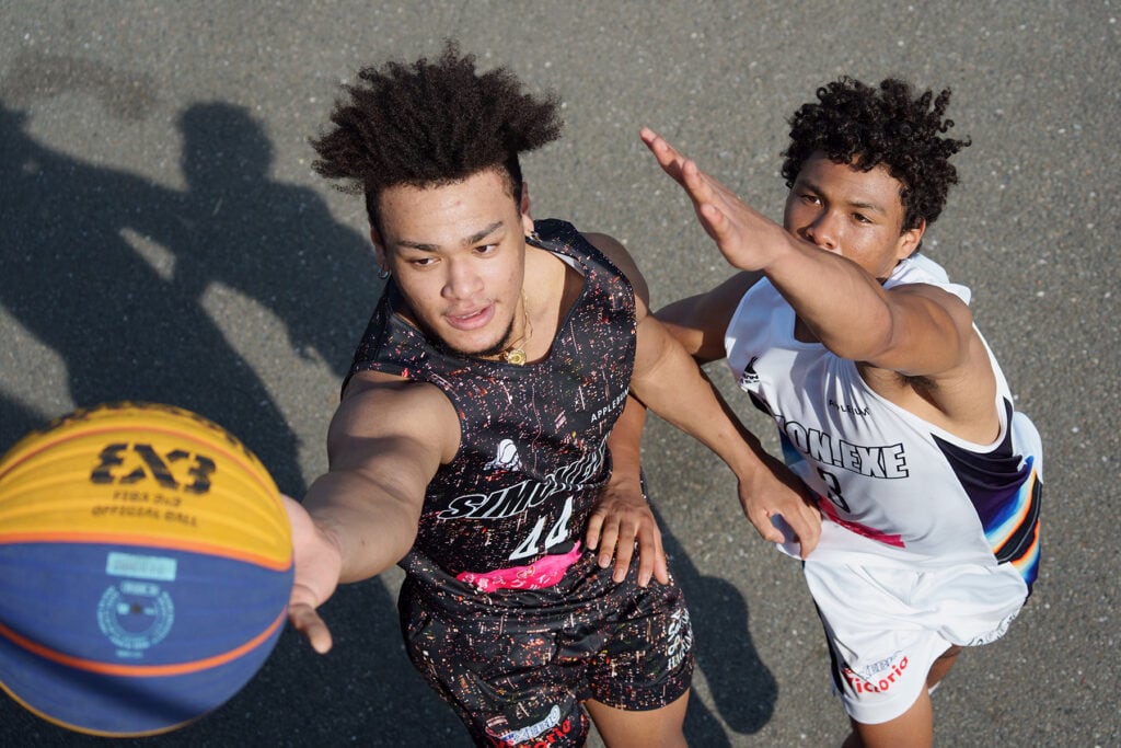 Dos jugadores de baloncesto en acción, uno de ellos alcanzando el balón durante un intenso partido.