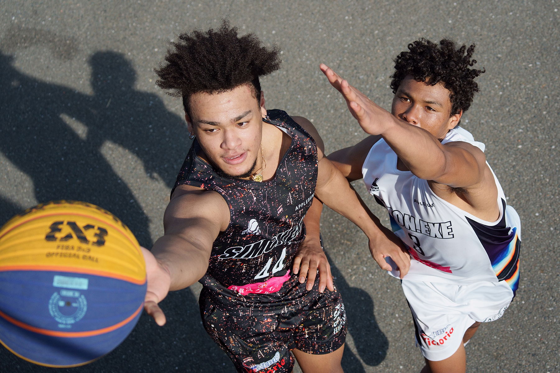 Dos jugadores de baloncesto en acción, uno de ellos alcanzando el balón durante un intenso partido.