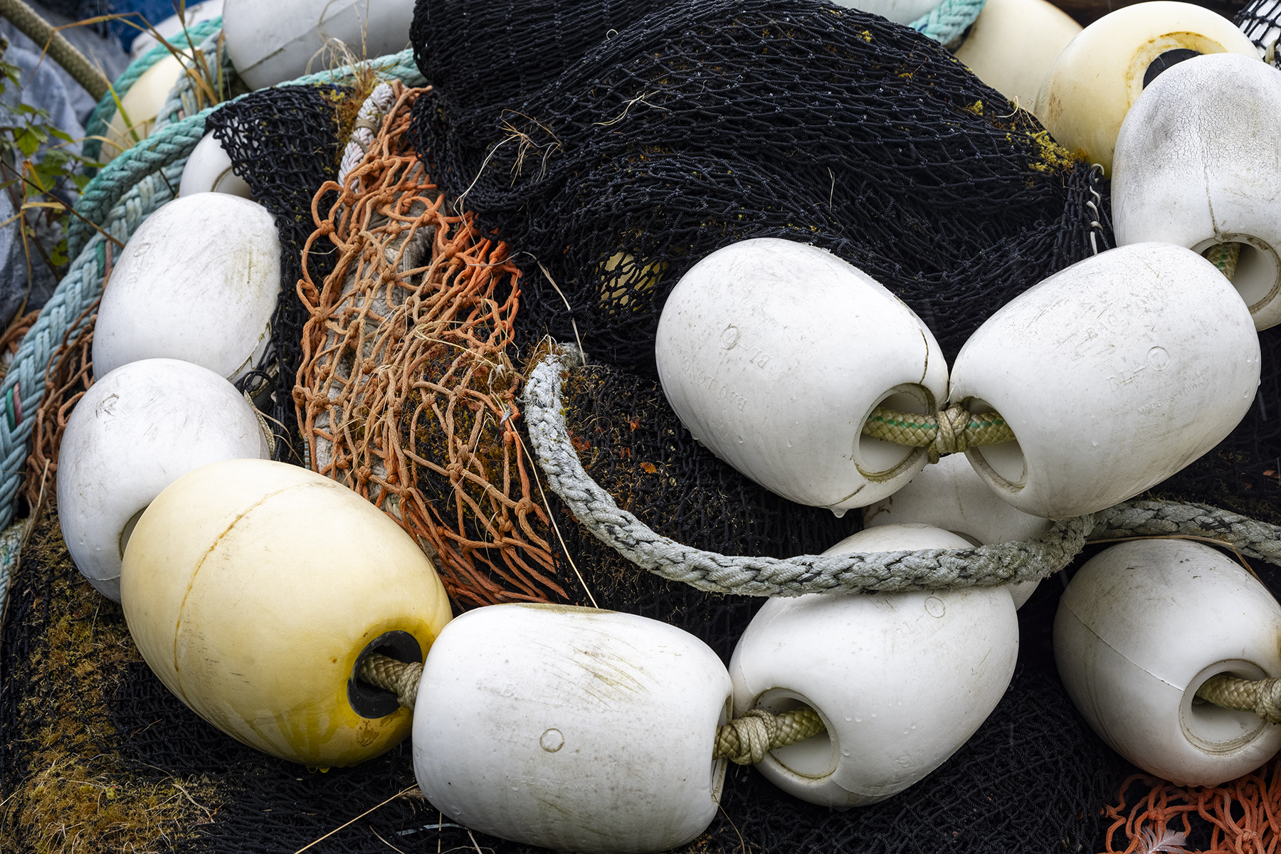 A pile of fishing gear, including nets, ropes, and white buoys, showcasing a rugged and well-used texture.