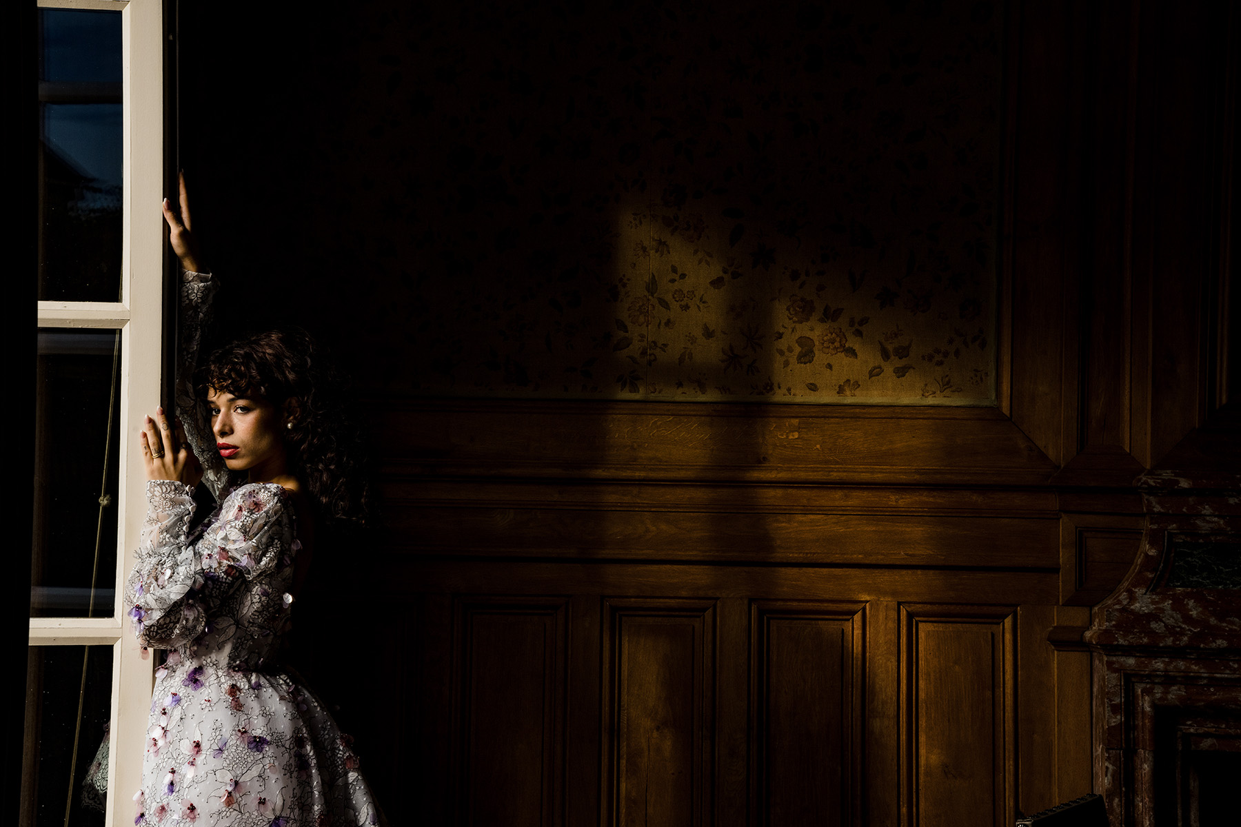 La suave luz de la ventana crea sombras y luces dramáticas, añadiendo profundidad y ambiente a este cautivador retrato.