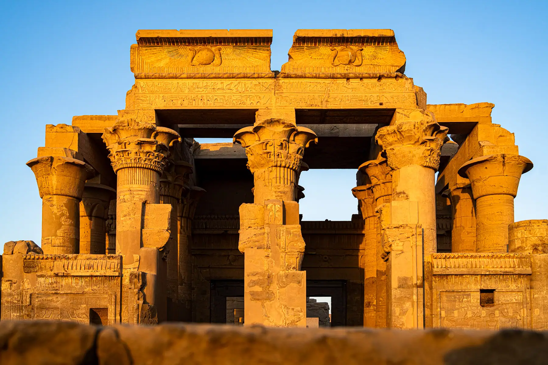 Golden sunlight hits the columns and carvings of the Temple of Kom Ombo in Egypt, a remarkable site to photograph historical landmarks in Egypt during Nile River travel.