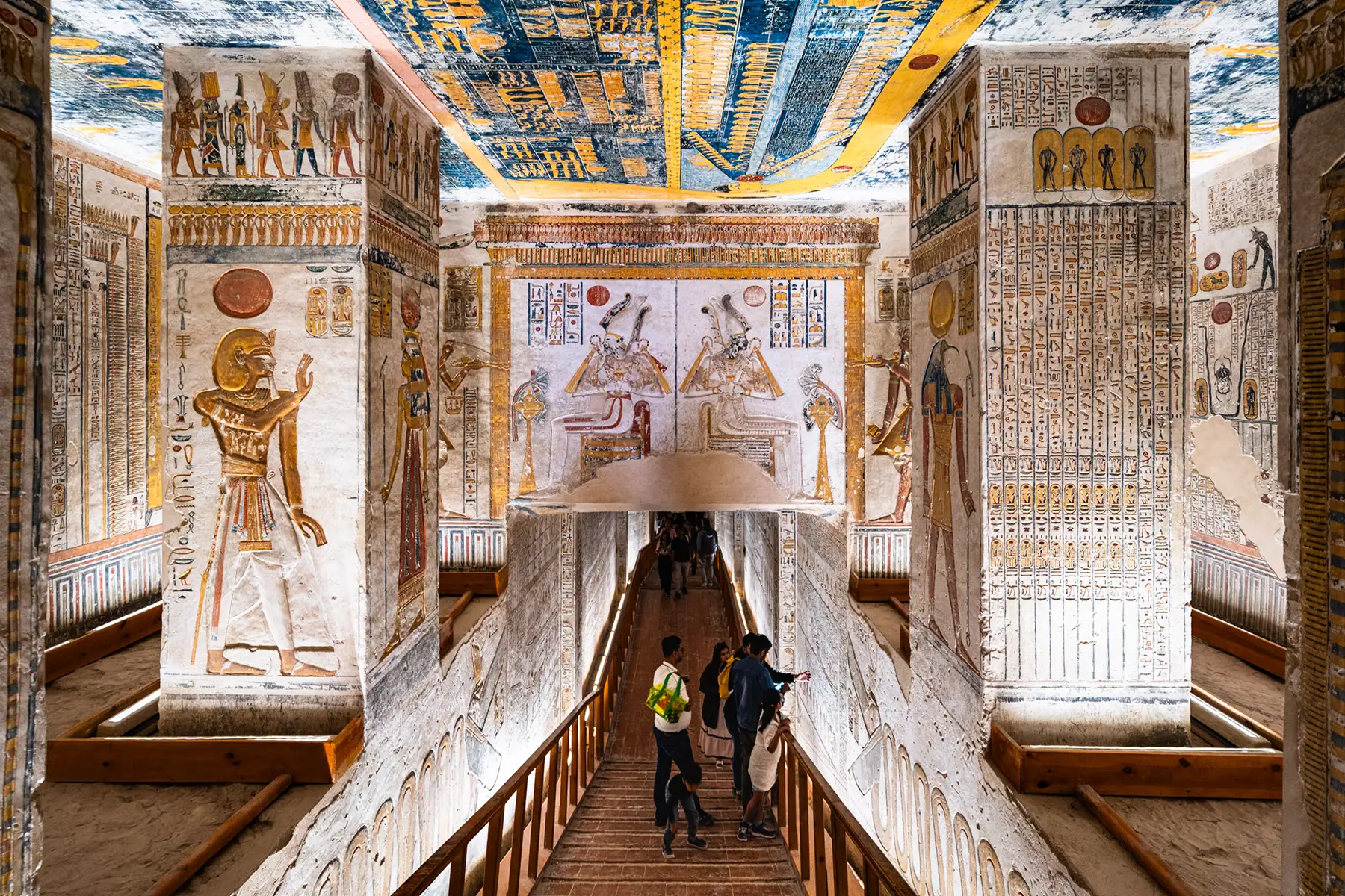 Visitors explore a vividly painted tomb interior in the Valley of the Kings, showcasing detailed hieroglyphs and deities&mdash;a powerful opportunity to photograph historical landmarks in Egypt.