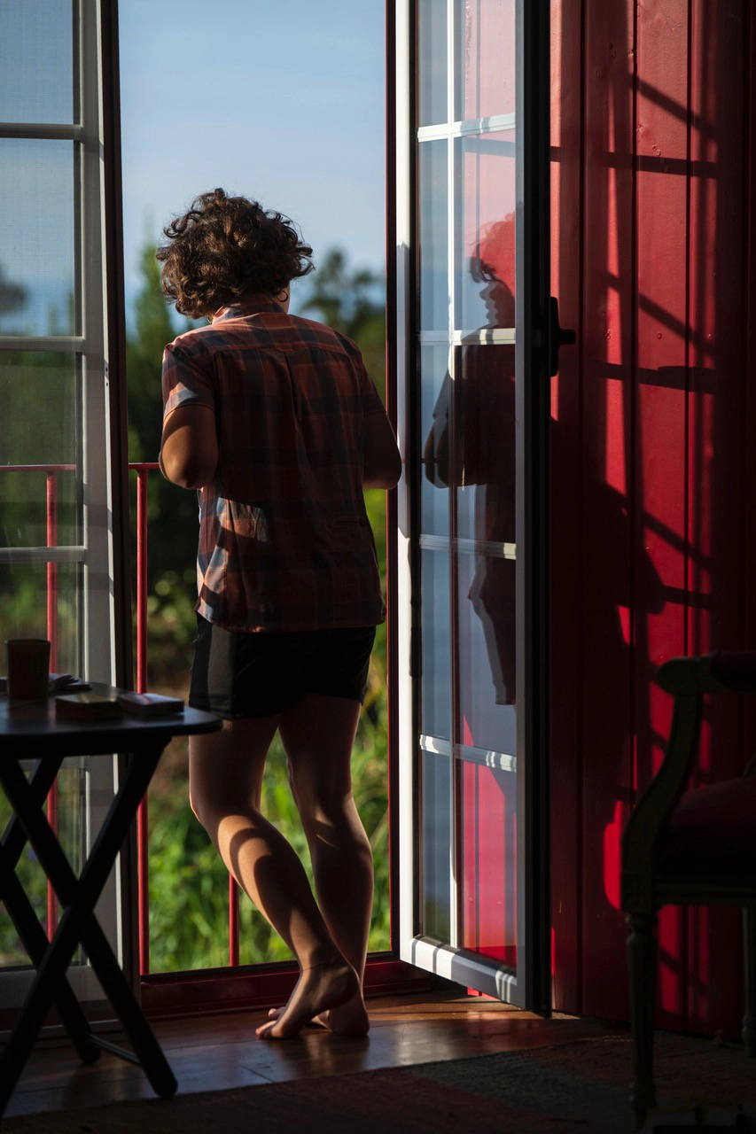 A child standing barefoot in the warm glow of early morning sun at an open doorway&mdash;capturing the fleeting quality of natural light when photographing portraits in early morning light.