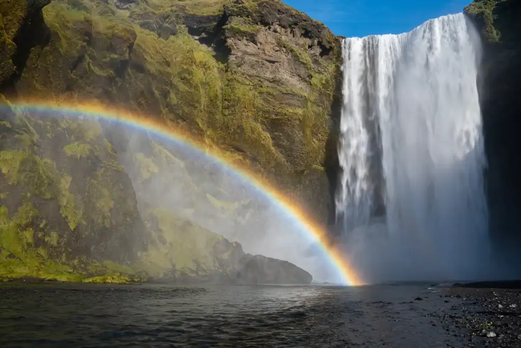 Skogafoss waterfall in Iceland with a rainbow over the water