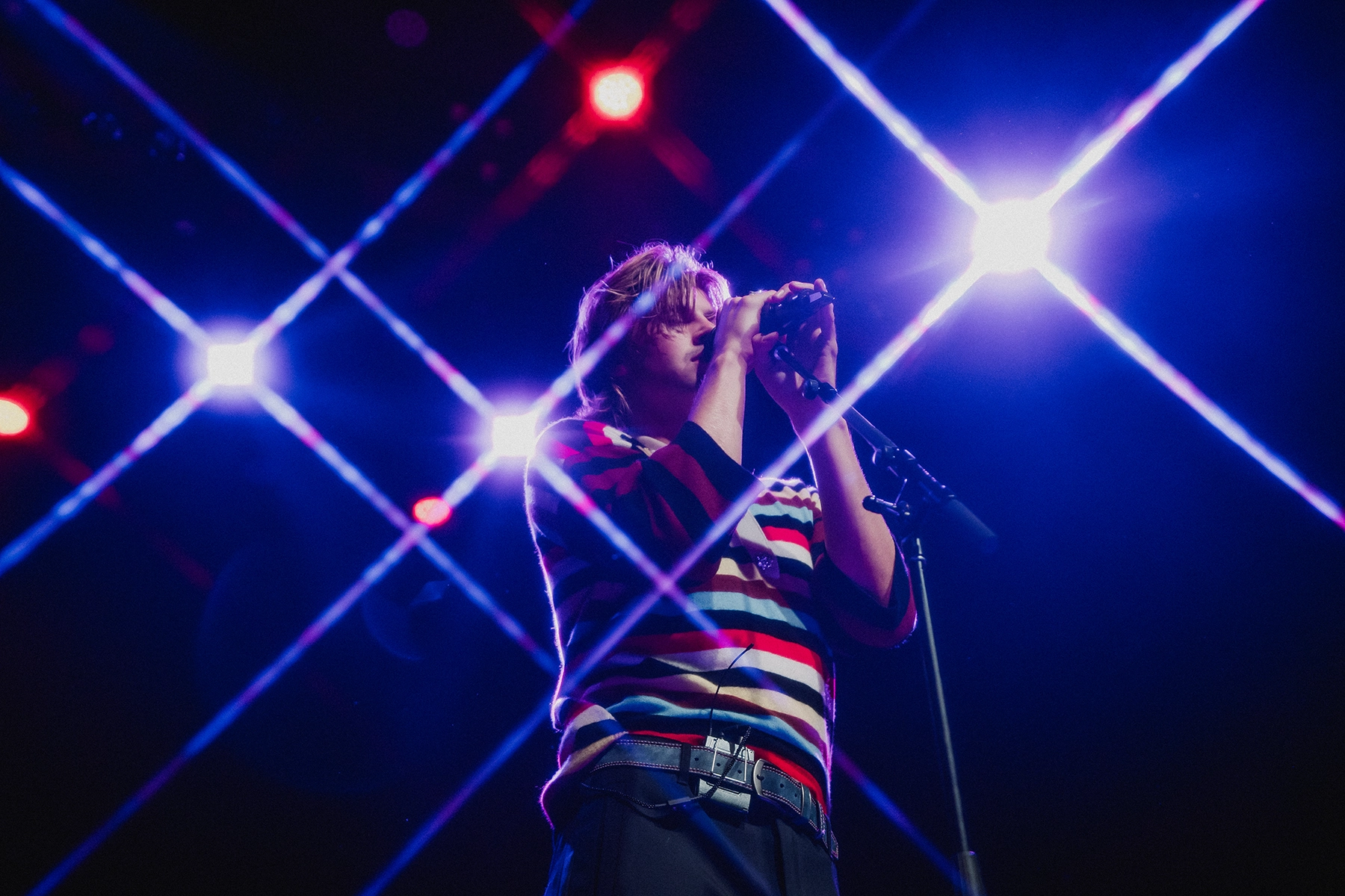 A male lead singer holding a microphone with twinkling lights around him