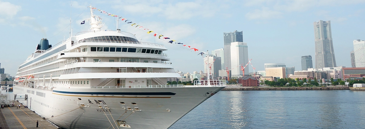 Un crucero atracado en Yokohama con el moderno horizonte de la ciudad al fondo, lo que demuestra que el mejor objetivo para fotografía de viajes capta tanto los grandes barcos como las detalladas escenas urbanas con una claridad vibrante.