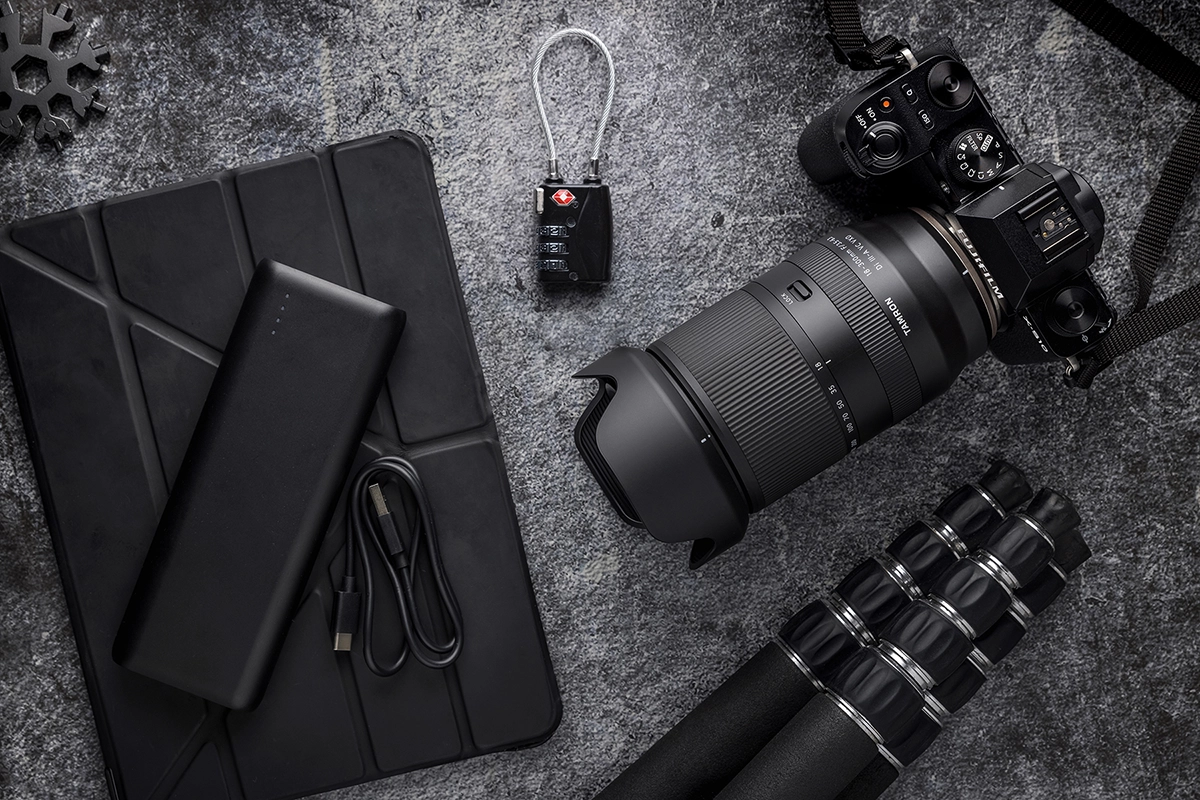 Equipo fotográfico de viaje que incluye un objetivo zoom Tamron montado en una cámara sin espejo, un trípode, una fuente de alimentación y una tableta, así como el mejor objetivo para fotografía de viajes que garantiza imágenes nítidas y versátiles en cualquier lugar.