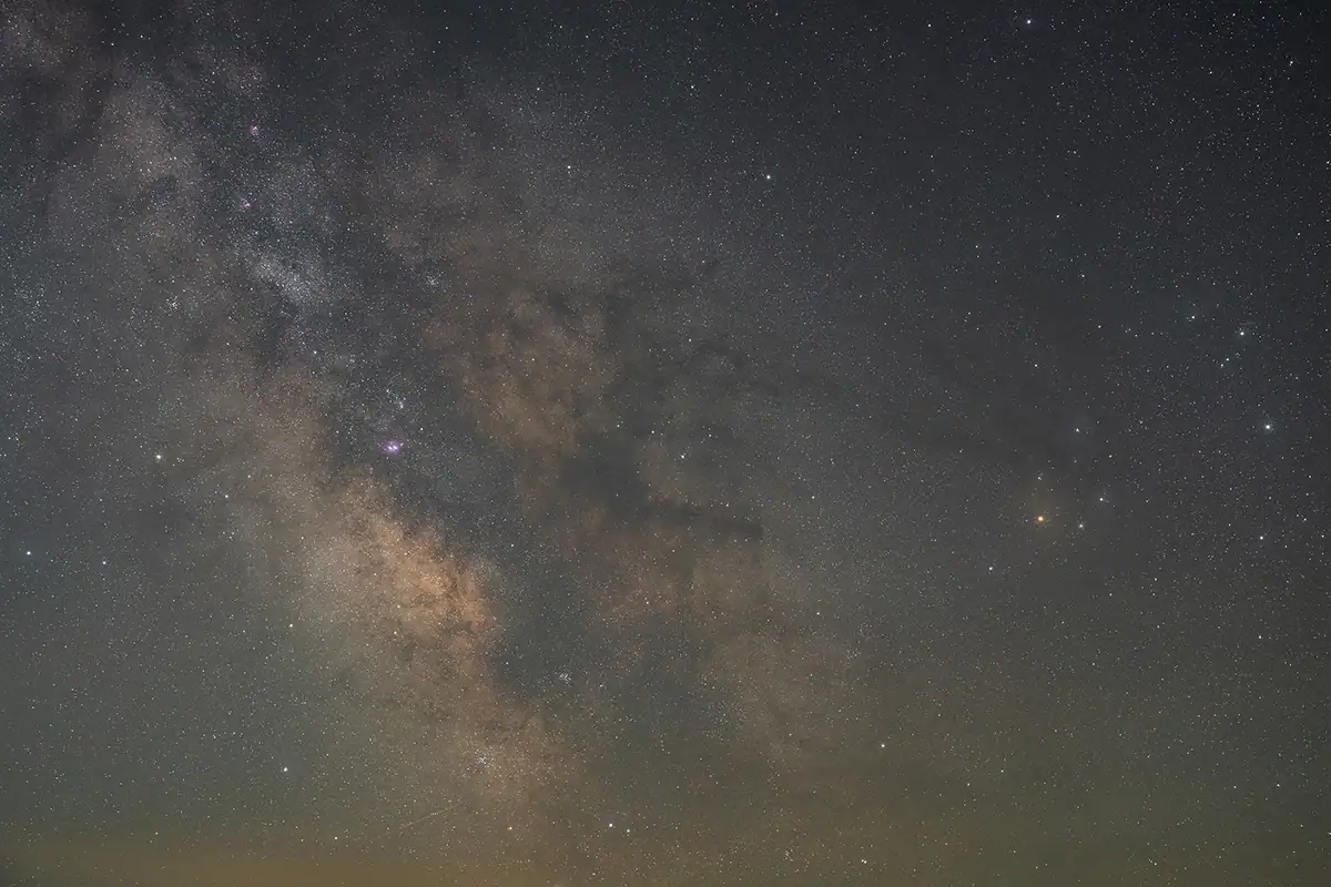 Vista detalhada da galáxia da Via Láctea mostrando nebulosas e aglomerados de estrelas capturados durante uma sessão de astrofotografia de céu profundo.