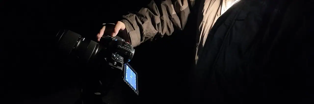 Fotógrafo usando o Astro Focus Lock no TAMRON Lens Utility™ à noite para obter um foco preciso durante uma sessão de astrofotografia em condições de pouca luz