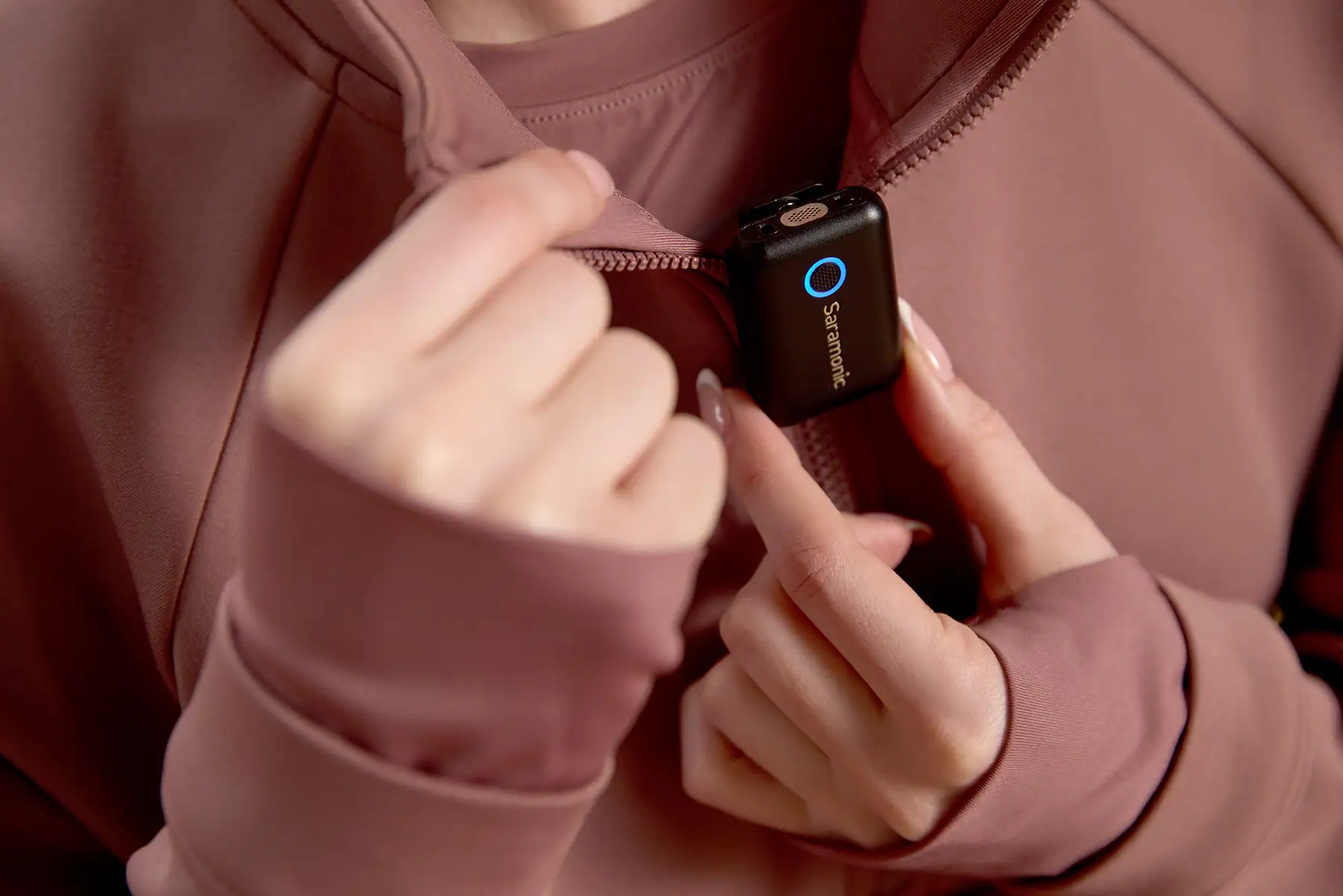 Using an external microphone by clipping a Saramonic wireless mic onto a jacket for clear audio in mobile video or livestream setups.