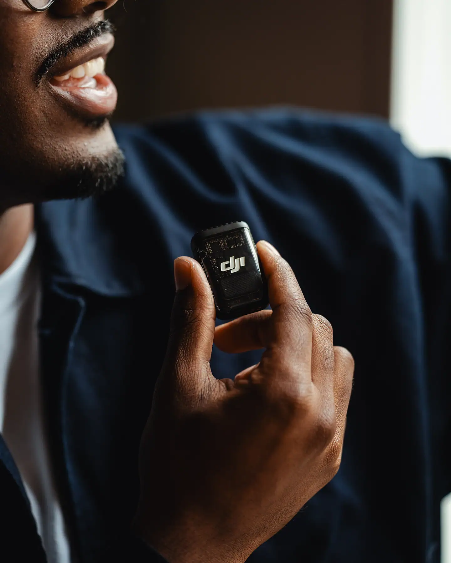 Creator using an external microphone, holding a compact DJI wireless mic near the collar for high-quality vocal audio.