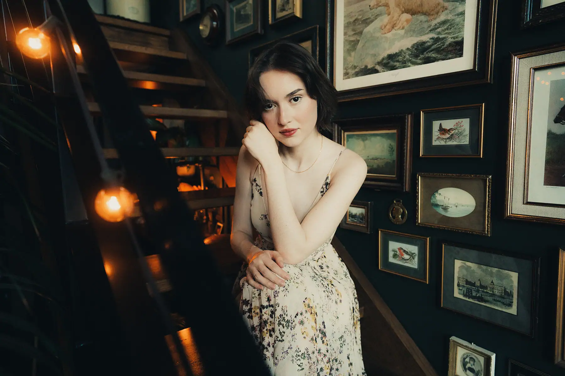 Uma mulher na escada, com luz natural em seu rosto, que cria um efeito luminoso, quase brilhante, em sua pele e faz com que seu rosto se destaque